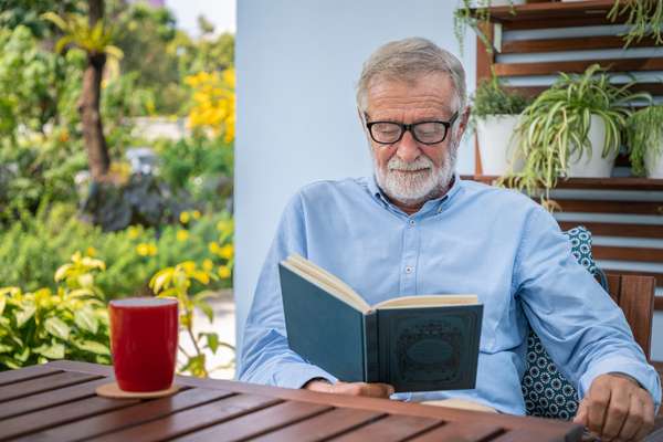 Older man reading on garden terrace